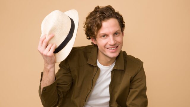 man wearing brown dress shirt holding white fedora hat